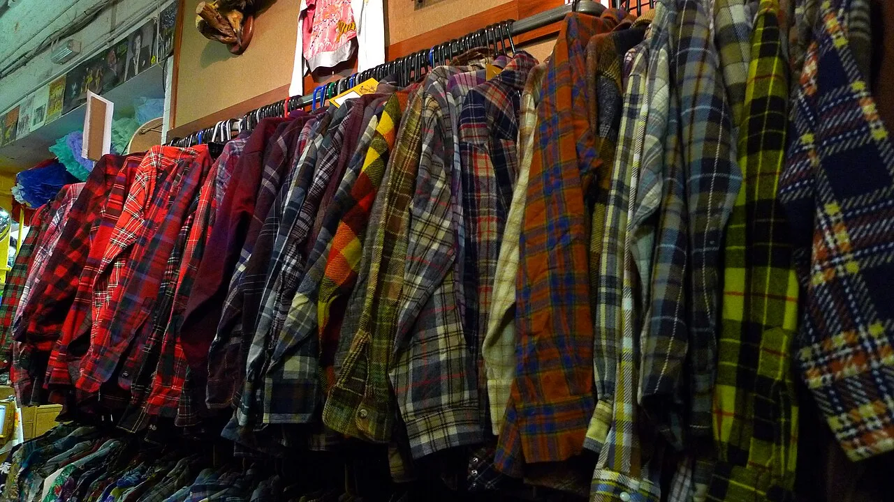 Camicie di seconda mano appese su uno stand di abbigliamento usato