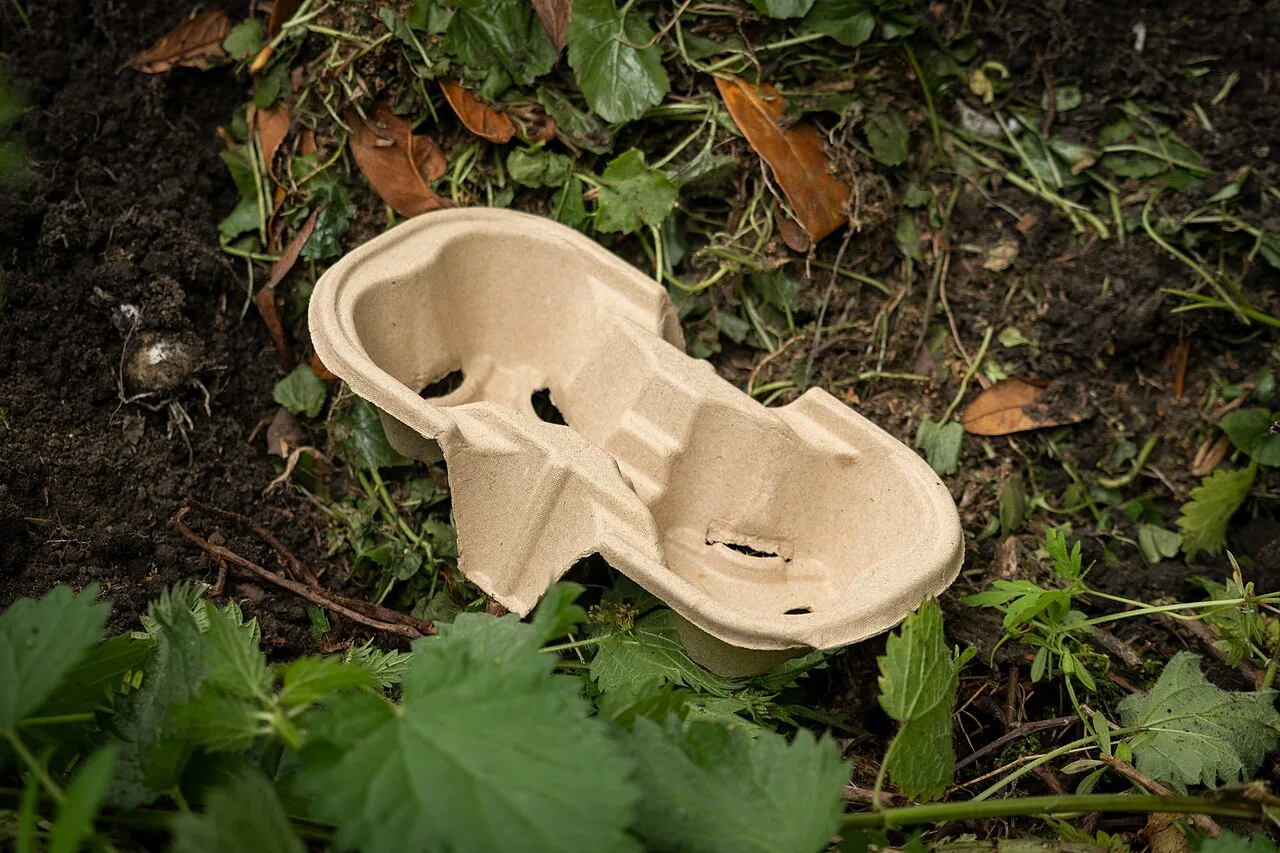 Porta bicchieri in cartone compostabile appoggiato sul compost