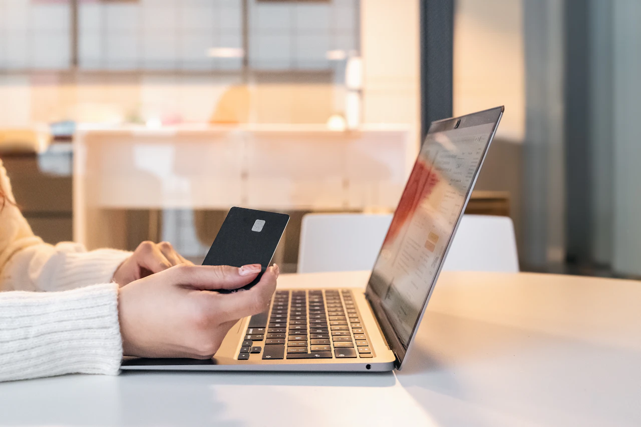 Donna davanti a un computer portatile con lo smartphone in mano