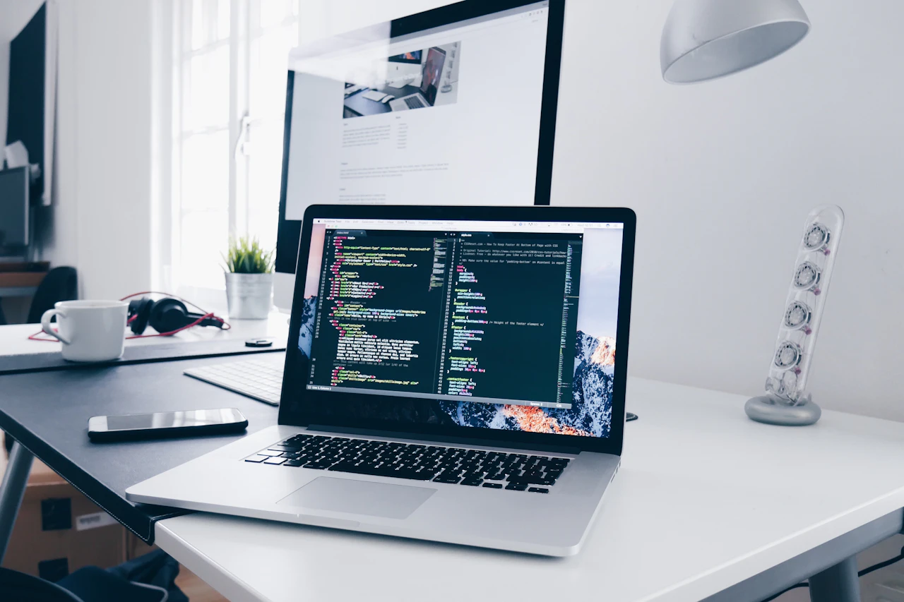 Computer portatile con righe di codice sullo schermo su una scrivania di lavoro